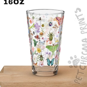 May include: A 16oz clear glass tumbler with a colorful design featuring butterflies, moths, beetles, and flowers. The design is printed on the entire surface of the glass.