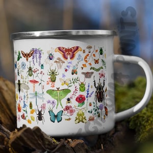 May include: White enamel mug with a colorful pattern of insects and flowers. The mug has a silver rim and handle.
