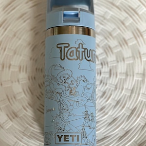 May include: A light blue Yeti water bottle with a stainless steel lid and a white outline of Toy Story characters on the side. The bottle has the text "Tatum" and "YETI" on it.