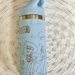 May include: A light blue stainless steel water bottle with a black lid and a carrying handle. The bottle has a silver bottom and a design of Woody and Jessie from Toy Story.