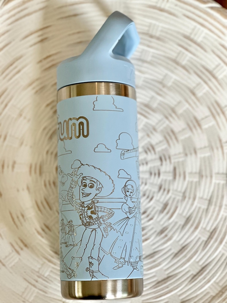May include: A light blue stainless steel water bottle with a black lid and a carrying handle. The bottle has a silver bottom and a design of Woody and Jessie from Toy Story.