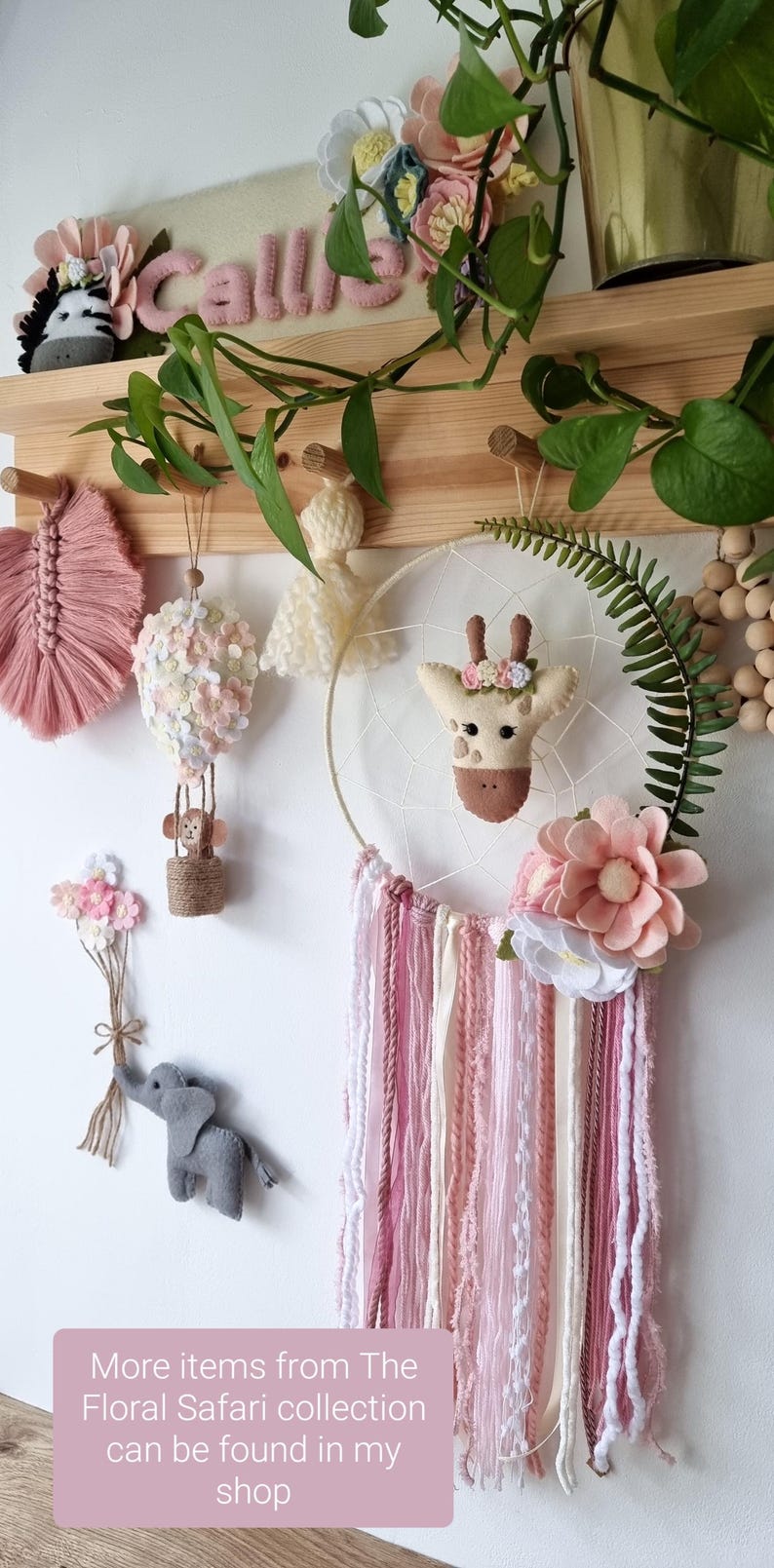 Pode incluir: Um conjunto de decora&ccedil;&atilde;o de ber&ccedil;&aacute;rio tem&aacute;tico floral rosa e branco com um apanhador de sonhos de girafa, um bal&atilde;o de ar quente, um macaco, um elefante e uma parede de penas. O apanhador de sonhos tem borlas de fio rosa e branco. O texto "Mais itens da cole&ccedil;&atilde;o Floral Safari podem ser encontrados na minha loja" est&aacute; na parte inferior da imagem.