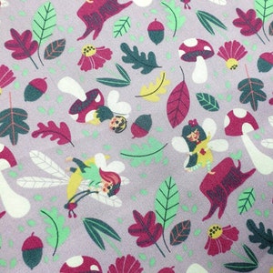 Può includere: Motivo ripetuto su sfondo lavanda con illustrazioni fantasiose. Il design include fate, funghi, ghiande, foglie e fiori nei toni del rosso, verde, giallo e bianco. Il tema generale è una scena fantasy o boschiva.