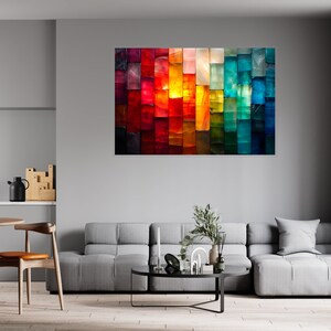 May include: An abstract artwork featuring a colourful array of vertical rectangles in shades of red, orange, yellow, green, and blue. The painting hangs on a grey wall in a modern living room, above a grey sofa. The room also has a round wooden table and chairs.