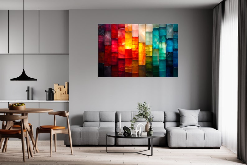 May include: An abstract artwork featuring a colourful array of vertical rectangles in shades of red, orange, yellow, green, and blue. The painting hangs on a grey wall in a modern living room, above a grey sofa. The room also has a round wooden table and chairs.