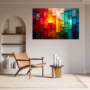 May include: A vibrant abstract artwork hangs on the wall, featuring a mosaic of vertical rectangular blocks in a rainbow of colours. The colour palette spans from deep reds and purples to bright oranges, yellows, greens, and blues. The room includes a leather chair and a small wooden table.