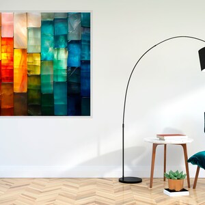May include: An abstract artwork in a white frame, displaying a colourful spectrum from red to blue. A black floor lamp, a teal chair with a white cushion, and a small side table are also visible in the room.
