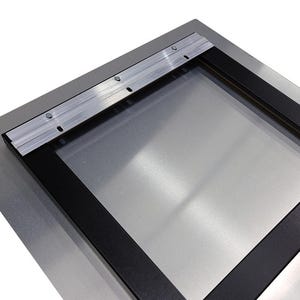 May include: A metal print with a black frame and a silver surface. The back has a metal hanging bracket attached with screws. The frame is rectangular.