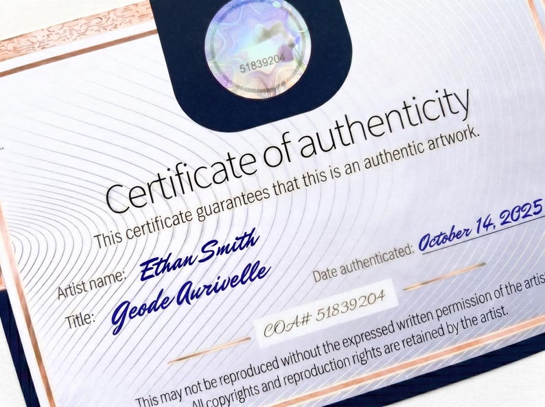 K&ouml;nnte beinhalten: Ein wei&szlig;es Echtheitszertifikat mit ros&eacute;goldenen R&auml;ndern und einem dunkelblauen oberen Bereich mit einem holografischen Siegel. Der Text lautet Certificate of authenticity, Artist name: Ethan Smith, Title: Geode Aurivelle, COA# 51839204 und October 14, 2025.
