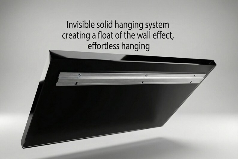 Pode incluir: Um painel retangular preto com um suporte met&aacute;lico de suspens&atilde;o integrado na parte traseira. O texto acima diz: Invisible solid hanging system creating a float of the wall effect, effortless hanging. O design permite a montagem na parede.
