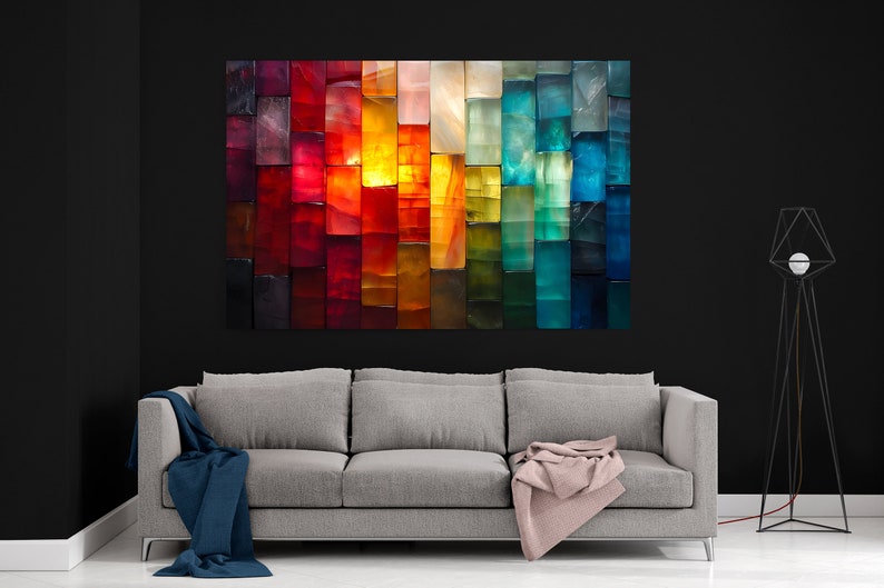 May include: A colourful abstract artwork, composed of vertical rectangular blocks in a gradient of colours. The piece, mounted above a grey sofa, transitions from red to blue. The room has a modern design with a black wall.