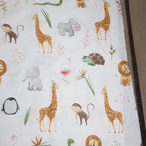 May include: White fabric with a repeating pattern of various animals including giraffes, lions, monkeys, hippos, flamingos, snakes, turtles, penguins, and elephants. The animals are illustrated in a cartoon style with watercolor-like details.