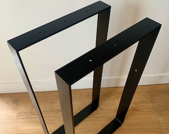 Könnte beinhalten: Zwei schwarze Tischbeine aus Metall in modernem, geometrischem Design. Jedes Bein hat eine quadratische V-Form mit vorgebohrten Löchern zur Befestigung. Die Beine bestehen aus robustem Metall und eignen sich für verschiedene Tischprojekte.