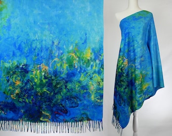 Puede incluir: Una bufanda de color azul y verde con estampado abstracto y flecos. La bufanda está drapeada sobre un maniquí.