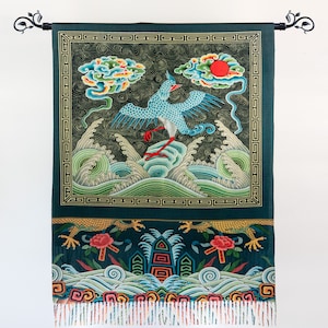 May include: A green tapestry with a blue bird flying over waves and a red sun. The tapestry has a gold border and a fringe at the bottom.