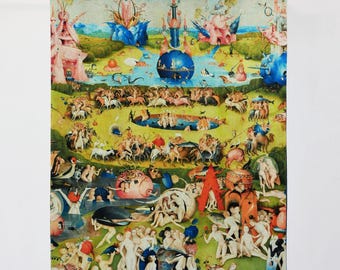 May include: A decorative tapestry displaying a vibrant, detailed painting with numerous figures and landscapes. The artwork is hung on a black metal rod with ornate ends. The tapestry has a fringed border at the bottom.