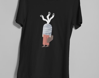 May include: Black t-shirt featuring a whimsical illustration. The design depicts a figure with a striped head and multiple white, eye-like tendrils. The figure is wearing orange pants and holding a brown bag. The shirt is held up by two hands.