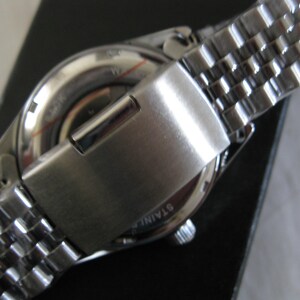May include: A silver wristwatch with a stainless steel band. The watch face is silver with black markings. The watch has a silver clasp.