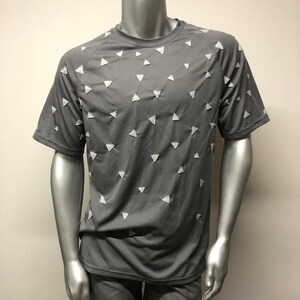 Puede incluir: Una camiseta gris de manga corta con un patrón de triángulos blancos.