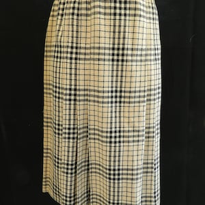 May include: A beige and black plaid skirt with a straight cut and a slightly flared hem.