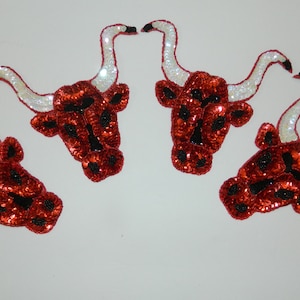 May include: Four red and black sequined bull head patches with white horns. The patches are perfect for adding a touch of western flair to clothing or crafts.