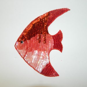 May include: A red and white angelfish made of sequins. The fish is about 6 inches long and 4 inches wide. It is a decorative item that can be used to add a touch of whimsy to any room.