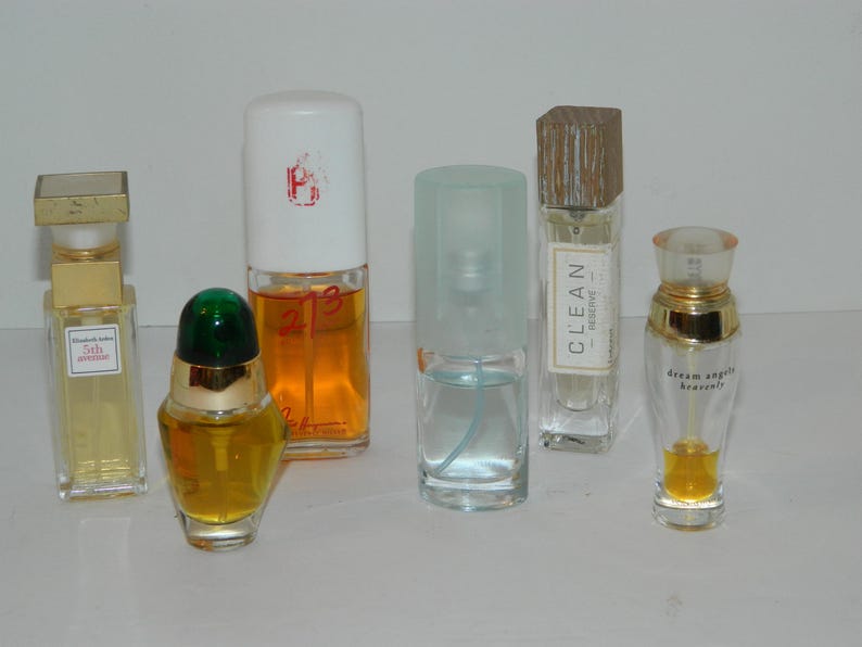 Puede incluir: Una variedad de frascos de perfume con varios dise&ntilde;os. Una botella tiene una tapa dorada, otra una tapa verde y una tercera una tapa de madera. Las botellas contienen l&iacute;quidos de diferentes colores, incluyendo amarillo y naranja.