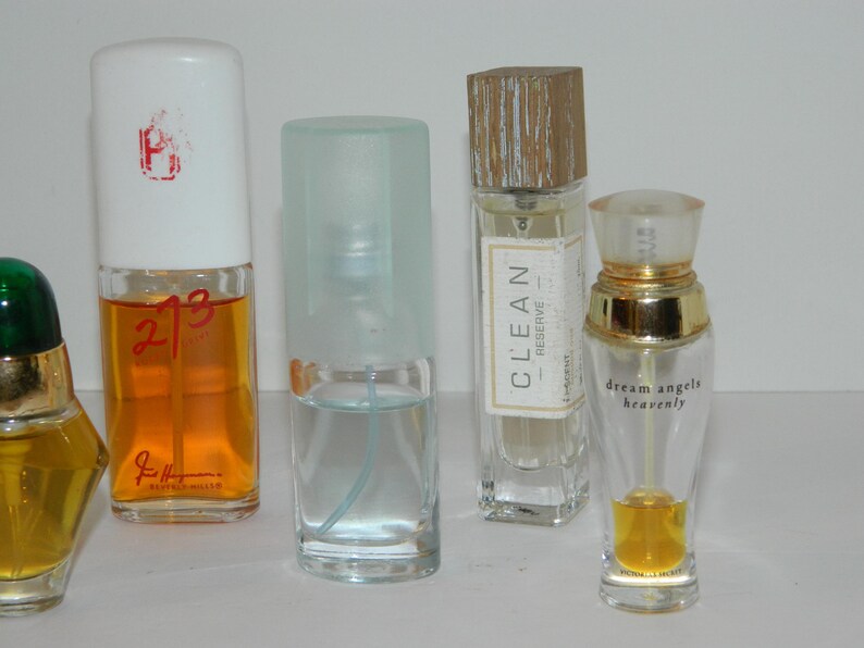 Puede incluir: Una colecci&oacute;n de frascos de perfume de varias formas y tama&ntilde;os. Uno tiene una tapa blanca con un dise&ntilde;o rojo, otro est&aacute; etiquetado como "CLEAN RESERVE", y un tercero dice "dream angels heavenly". Los frascos contienen l&iacute;quidos de diferentes colores.