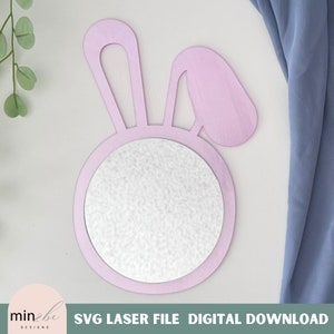 May include: A pink wooden bunny rabbit mirror with a round mirror in the center. The mirror is perfect for a child's room or nursery.