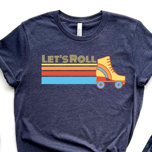 May include: A navy blue t-shirt with a retro-style graphic of a roller skate and the text "Let's Roll".