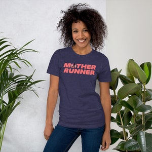 May include: A woman wearing a navy blue t-shirt with the text "MOTHER RUNNER" in pink. The text includes a small graphic of a running person with an American flag design.