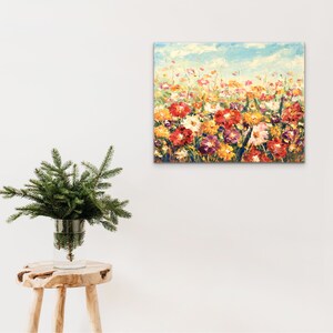 May include: A colorful painting of a field of flowers in various shades of red, yellow, orange, and pink. The flowers are painted in a loose, impressionistic style, with visible brushstrokes. The background is a soft blue sky with white clouds.