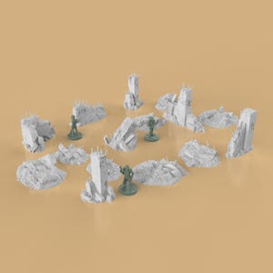 May include: A collection of miniature, gray, ruined building structures and rubble, likely for tabletop gaming or model building. Several small, green figurines are interspersed among the debris, suggesting a post-apocalyptic or war-torn theme.