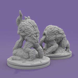 K&ouml;nnte beinhalten: Zwei graue Monsterfiguren mit detaillierten, strukturierten Oberfl&auml;chen. Eine steht aufrecht, die andere hockt. Beide stehen auf runden, rissigen Sockeln. Der Hintergrund ist einfarbig lila. Diese Figuren scheinen Fantasy- oder Science-Fiction-Themen zu haben.