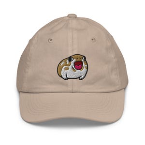 May include: A beige baseball cap with an embroidered image of a brown and white frog with a pink open mouth. The frog is looking to the right.