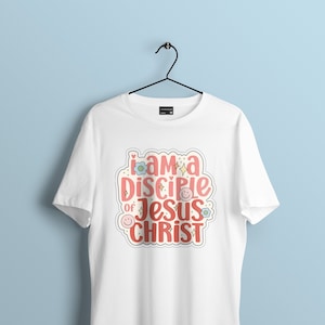 May include: White t-shirt with a pink graphic that says "I am a disciple of Jesus Christ" with colorful flowers and smiley faces.