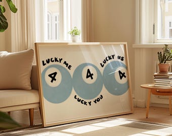 May include: A framed art print featuring three light blue billiard balls with the number 4 and the words "Lucky Me", "Lucky You", and "Lucky Us" in black. The artwork is displayed in a bright, airy room.