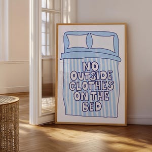 May include: A blue and white striped poster with a cartoon bed and pillows. The text on the poster reads "No outside clothes on the bed."