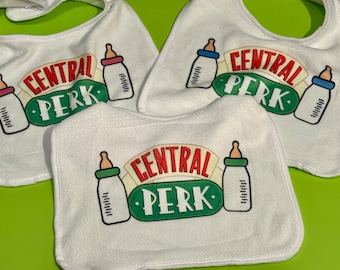 May include: Three white baby bibs with a green, red, and white "Central Perk" logo and a baby bottle graphic.