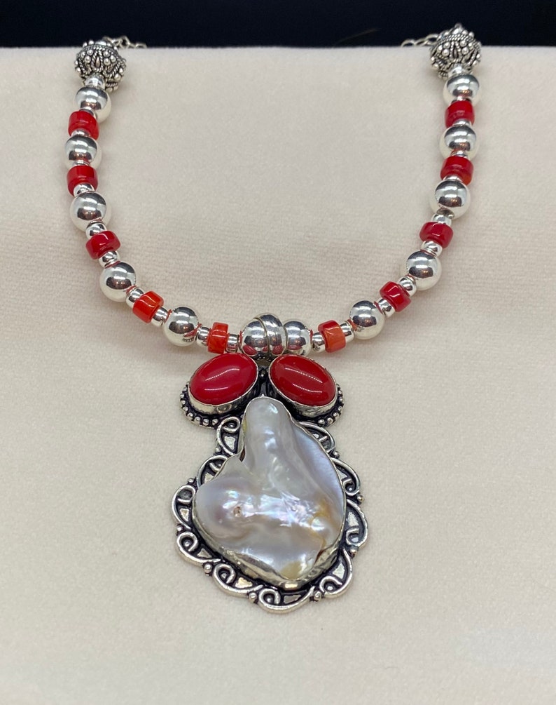 Distinctive pendant of shell and coral set in sterling silver is featured in this handmade necklace