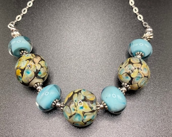 Mesmerizing handmade robin egg blue and earthy brown lampwork glass beads are paired with sterling silver in handmade necklace