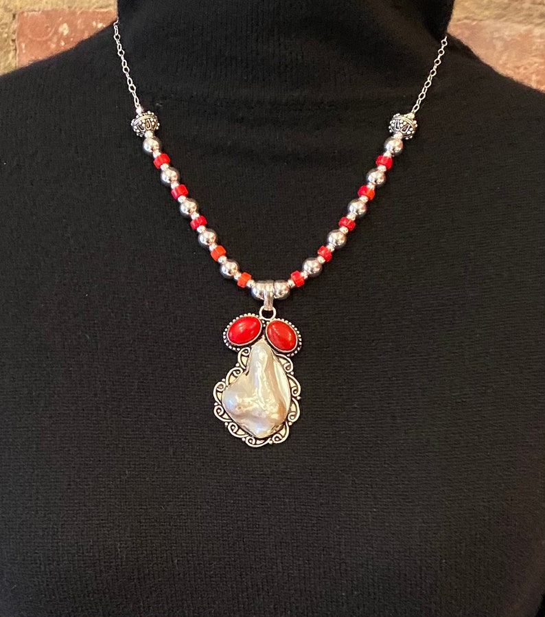 Distinctive pendant of shell and coral set in sterling silver is featured in this handmade necklace