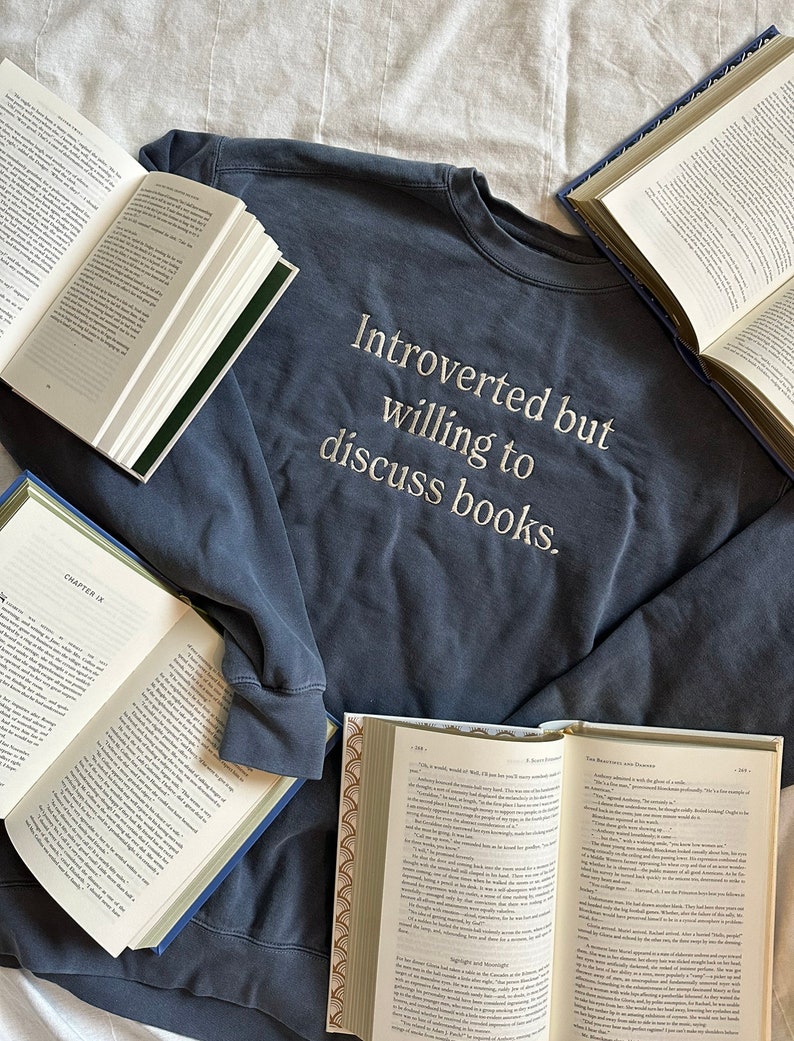 Może przedstawiać: Granatowa bluza z haftem "Introvert, ale chętny do dyskusji o książkach" na przodzie.