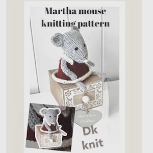 May include: A knitted gray mouse wearing a burgundy dress with a white collar, sitting on a decorative box. The image includes the text "Martha mouse knitting pattern" and a small heart-shaped tag that says "Have a mice Christmas".