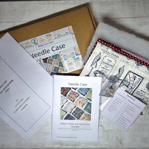 May include: A needle case making kit with fabric, wadding, and instructions. The kit includes patterned fabric, a red and white polka dot fabric, and a cream fabric with a vintage design. The kit is packaged in a brown cardboard box, ideal for a sewing project.