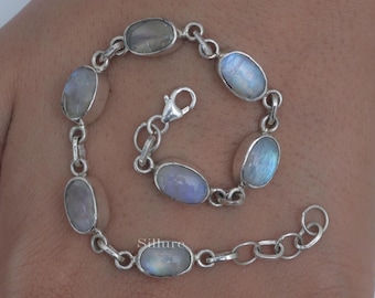 May include: A silver chain bracelet featuring six oval-shaped, iridescent moonstone cabochons set in polished metal bezels. The bracelet includes a lobster claw clasp and an adjustable extender chain with circular links. The word Sillure is visible.