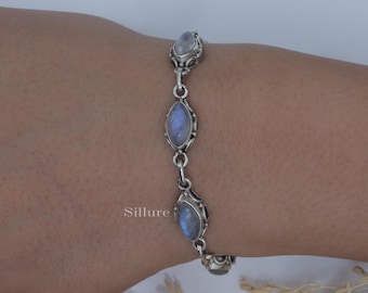 Op de afbeelding: Een zilveren armband met drie ovale maansteen edelstenen. De armband is verbonden door sierlijke schakels en wordt op een arm getoond. Het woord "Sillure" staat op de arm.