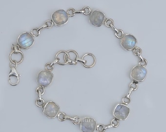 May include: A silver chain bracelet featuring seven square-cut, translucent moonstone cabochons set in polished metal frames. The bracelet includes a lobster claw clasp and a series of circular jump rings for adjustable sizing, with the word Sillure printed.