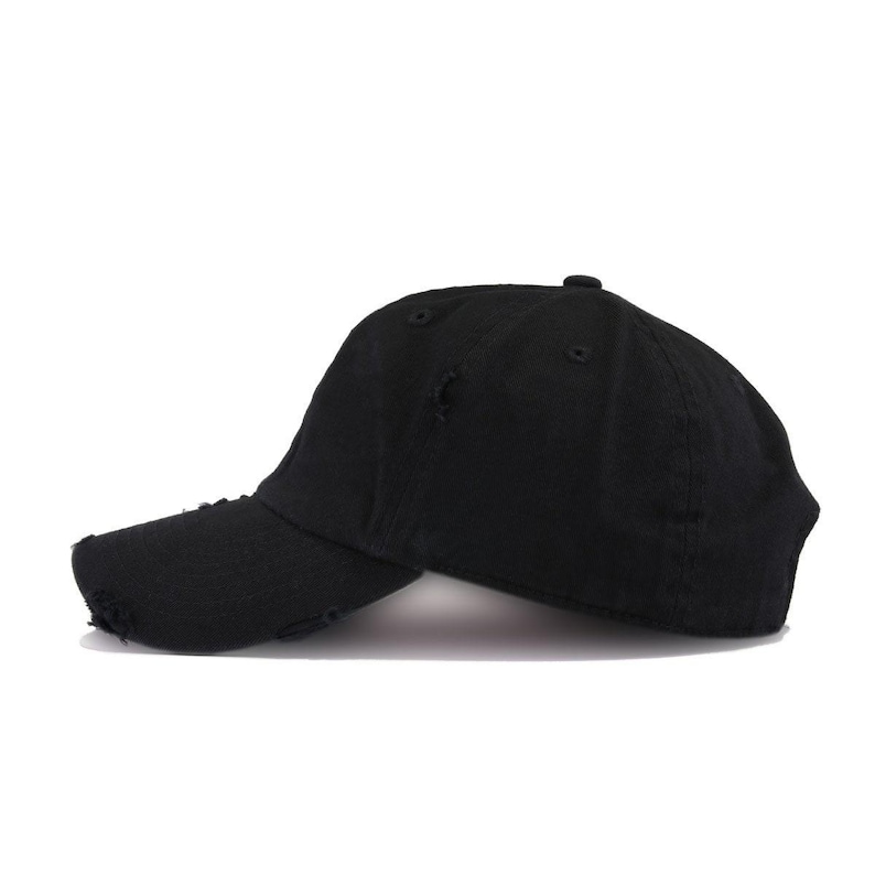 May include: A black distressed baseball cap with a slightly curved brim. The cap has a worn look with small holes and frayed edges.