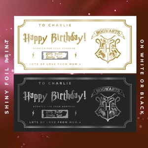 K&ouml;nnte beinhalten: Eine wei&szlig;e und schwarze druckbare Karte mit goldener und silberner Schrift. Die Karte sagt "Happy Birthday!" und "An Charlie". Sie hat auch einen Rubbelbereich, auf dem "Harry Potter Studio Tour" steht. Die Karte hat ein Hogwarts-Wappen darauf.